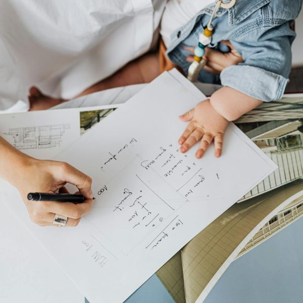 Woman holding her child as she writes down her notable highlights, looks through imagery, and decides what should go into her digital media kit.