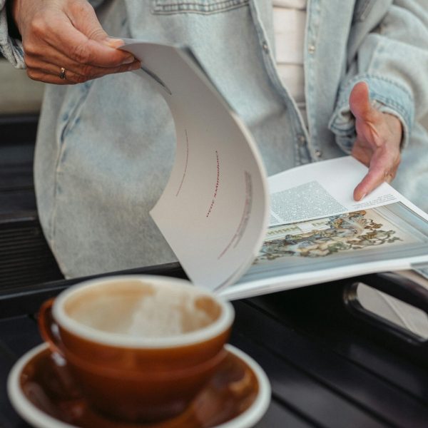 A woman looking at a story in a magazine, preparing to write a media pitch for herself.